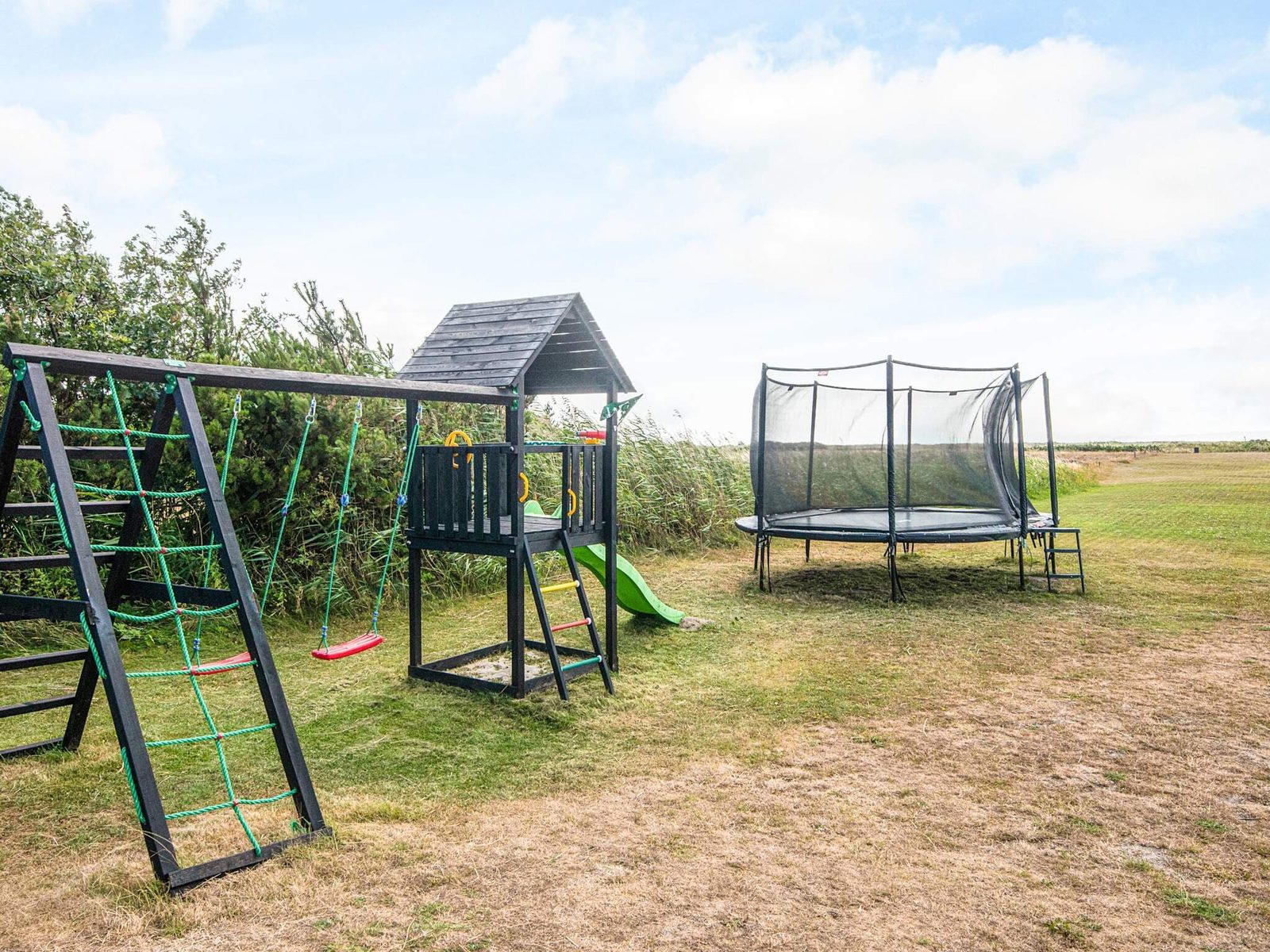 Climbing frame with cargo net, slide and trampoline