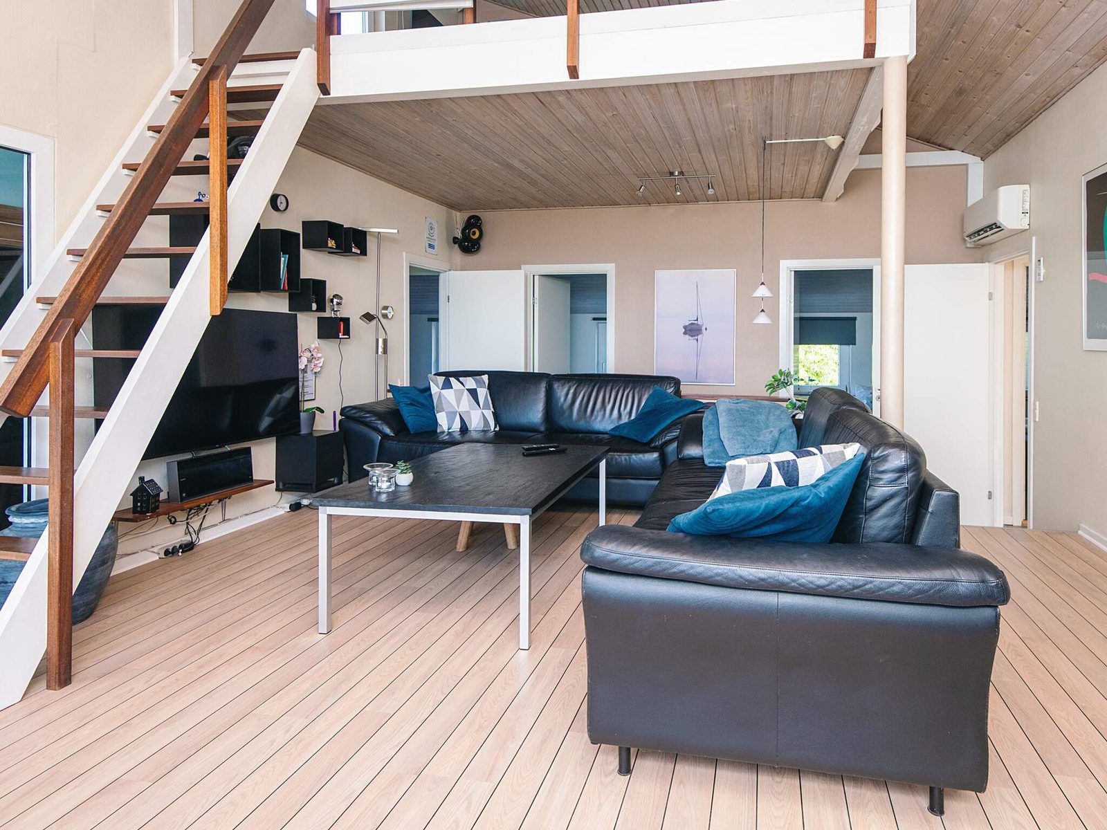 The living room, with sloping timber ceilings and stairs to the loft