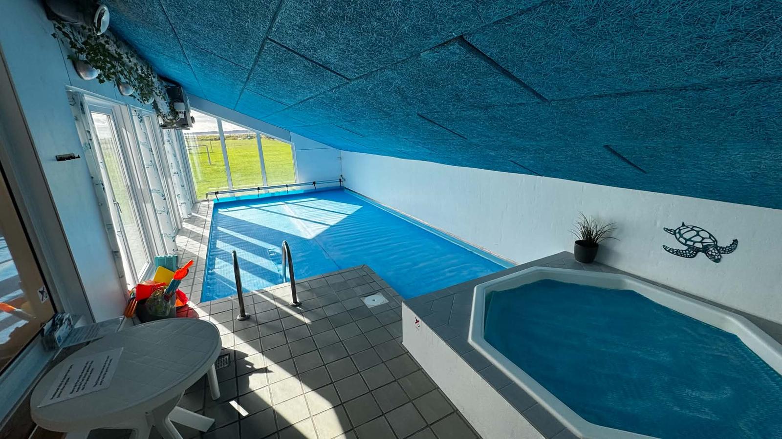 Poolrummet med whirlpoolen forrest og plænen bag vinduerne