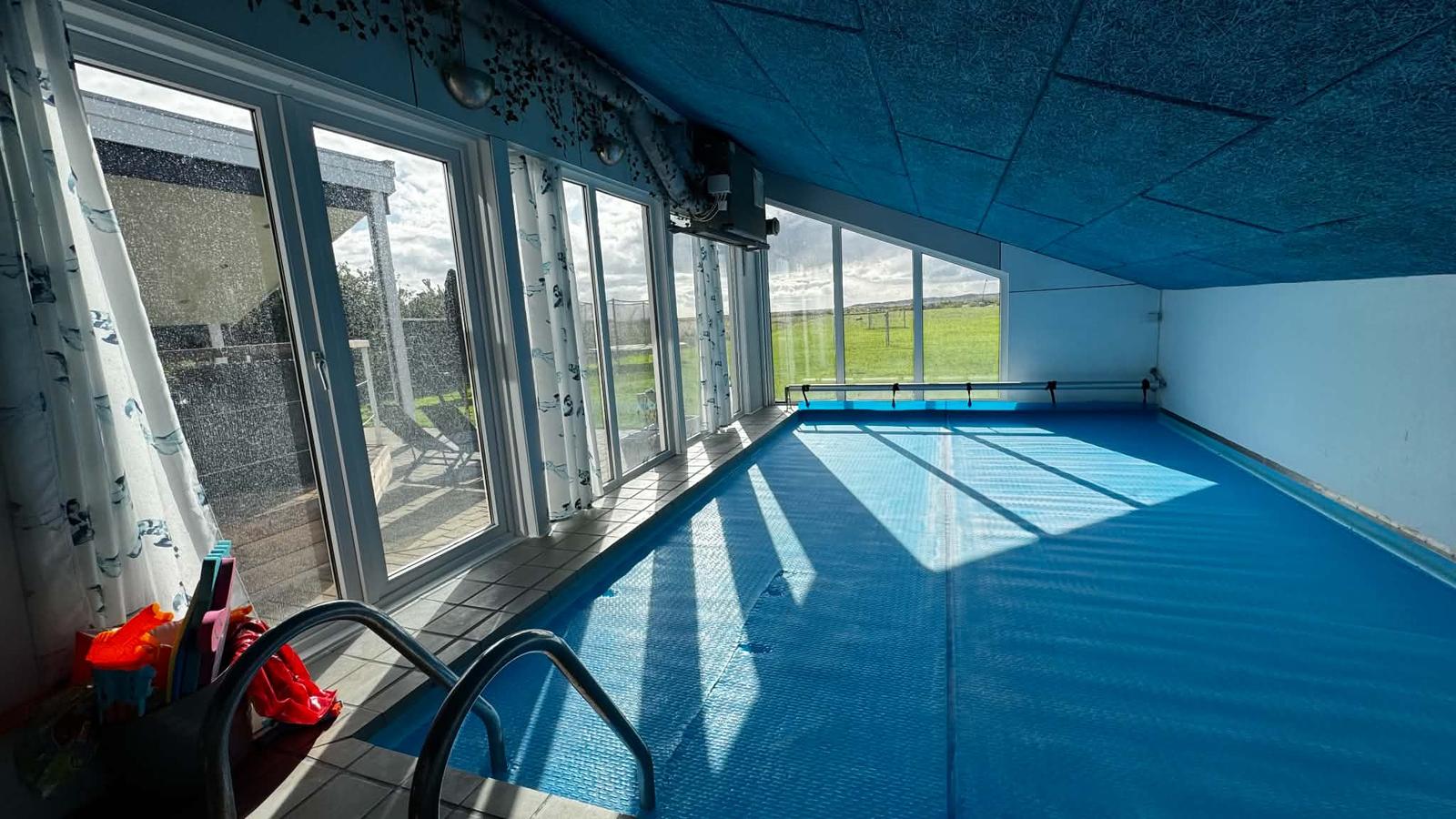 Poolen langs glasfacaden mod terrassen og plænen
